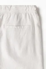 Short color crema en tejido liviano de algodón y viscosa. Modelo con cierre decorativo, elástico revestido con cordón para ajustar en la cintura, bolsillos al bies y bolsillo insertado atrás. Corte relajado para una silueta casual.