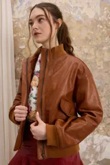 Chaqueta de cuero color marrón con cuello alto y puños de algodón. Cierre delantero con cremallera y dos bolsillos laterales. Talle único.