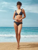 Conjunto de bikini azul oscuro con corpiño triangular con volados en los breteles y bombacha con volados en la cintura.
