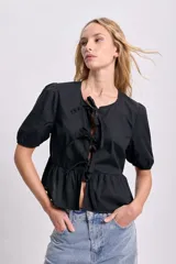 Blusa negra con escote redondo y mangas cortas abullonadas. Presenta lazos frontales para ajustar el escote y un corte con frunce en la cintura.