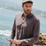 Camisa de lino color gris topo, de corte clásico, con cuello abotonado, manga larga y bolsillo en el pecho.