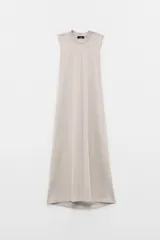 Vestido largo color beige, sin mangas, con cuello a la base y caída amplia. Confeccionado en tela estilo jogging.