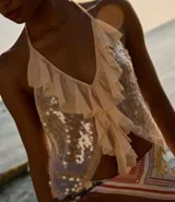 Blusa color rosa pálido con lentejuelas y volados, de escote halter y espalda descubierta.