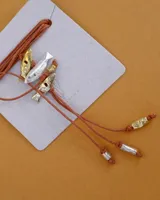 Gargantilla con hilo de algodón color camel y tres dijes de peces realizados en bronce, alpaca y plata 925.