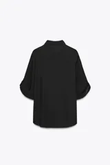 Camisa negra de Zara Woman Collection confeccionada en hilatura con mezcla de viscosa y lyocell. Tiene cuello solapa, manga por debajo del codo ajustable con trabilla y botón, bolsillo de plastrón en el pecho, bajo asimétrico redondeado y cierre frontal con botones.
