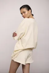 Remerón de manga corta color crema, corte oversize y cuello redondo. Estampado frontal con texto y un dibujo de una persona nadando, con la frase "The Peel Swim Club".