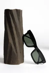 Lentes de sol negros con marco rectangular y lentes verdes.