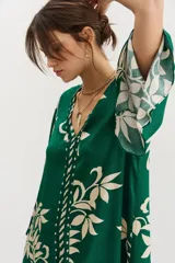 Vestido midi verde con estampado de hojas color crema, escote en V y mangas 3/4 amplias.
