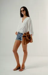 Blusa blanca de manga tres cuartos con cuello en V y textura sutil, corte holgado.