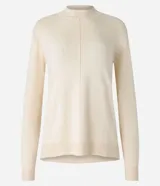 Blusa de punto color crema, con cuello alto y mangas largas.