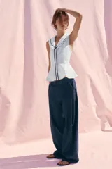 Top blanco de popelina con cuello marinero, escote pico, sin mangas y lazo negro en el frente.