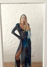 Vestido largo de microtul con estampado abstracto en tonos azules y negros. Tiene escote en V con lazo ajustable y mangas largas acampanadas.
