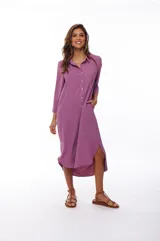 Vestido camisero midi color lila, de corte recto, con cuello camisero, mangas 3/4, cierre frontal con botones y aberturas laterales.