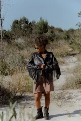 Campera de cuero negra con flecos largos en el ruedo, corte biker clásico con detalles metalizados, cinto regulable e interior forrado.