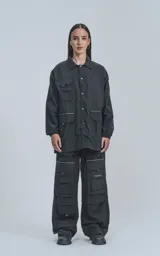 Campera negra oversize con broches en el delantero, forrada con red, múltiples bolsillos con detalles réflex y puños elásticos.