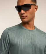 Remera deportiva gris con cuello redondo, mangas cortas, estampa heat print y detalle en los hombros. Confeccionada en tejido de malla con tecnología Dry.