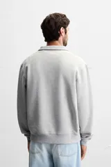 Sudadera color crema de corte recto, con cuello polo y cierre de cremallera metálica.