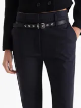 Pantalón sastrero negro con raya marcada al centro y pierna recta. Incluye un cinturón desmontable de cuero vacuno con herrajes metálicos. Tiene bolsillos delanteros biselados y un bolsillo ojal en la espalda.