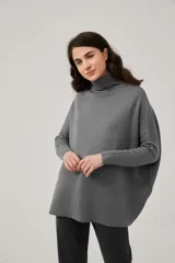 Polera gris holgada de acrílico, con cuello alto y mangas largas.