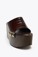 Mules con plataforma de madera y capellada marrón con textura de piel de cocodrilo.
