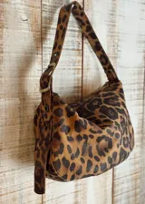 Bolso de hombro color blanco con textura craquelada, correa regulable con hebilla, interior forrado y cierre superior. Incluye llavero y bolsillos internos.