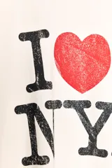 Remera color crudo de corte holgado con mangas cortas y cuello redondo. Estampado frontal con el texto "I ❤️ NY" en color negro y rojo.