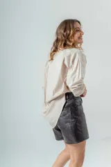 Camisa color beige de corte clásico, con cuello camisero, mangas largas con puños abotonados y cierre frontal con botones.