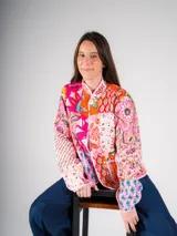 Chaqueta con cuello alto y botones tipo nudo, confeccionada con la técnica patchwork, combinando retazos de telas tradicionales con bordados y estampados vibrantes que mezclan flores, formas geométricas y cultura textil.