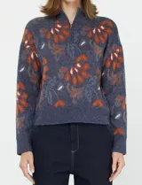 Buzo de tejido de punto azul marino con estampado floral en tonos terracota y verde azulado. Presenta cuello alto con cierre parcial frontal y puños y ruedo acanalados.