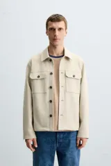 Sobrecamisa color beige de tejido efecto ante, corte regular fit, con cuello solapa, manga larga con puños abotonados, bolsillos de parche con solapa en el pecho y bolsillos de ojal en la cadera.