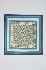 Pañuelo cuadrado con estampado geométrico en tonos verde oliva y blanco, enmarcado por bordes concéntricos en azul oscuro, celeste y beige.