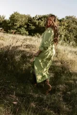 Vestido midi verde pistacho, con corte camisero, mangas 3/4 con volados y falda con abertura lateral. Incluye cinturón de la misma tela.