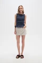 Falda mini color beige, de jean rígido, con bolsillos delanteros y traseros.