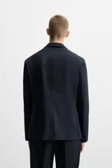 Blazer azul marino de corte recto, con cuello de solapa de muesca, cierre frontal con dos botones, bolsillos de solapa en la cadera y aberturas en la espalda. Confeccionado en tejido de algodón con elasticidad y sin forro interior.