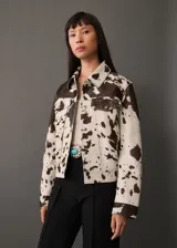 Chaqueta con estampado de vaca, diseño recto y cuello camisero, con dos bolsillos de solapa en el pecho y cierre delantero de botones.