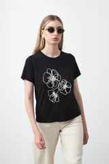 Remera de manga corta color negro con cuello redondo y un bordado floral en relieve de tres flores en hilo blanco en el frente.