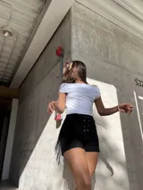 Short negro de bengalina elastizada con cintura alta, cordones cruzados en el frente y flecos en los laterales.