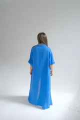 Camisola larga azul francia de lino italiano, con cuello camisero, mangas largas con puños abotonados, cierre frontal con botones y bolsillos de parche en el pecho.