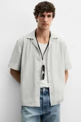 Camisa de manga corta con cuello bowling y corte relaxed fit, confeccionada en tejido con algodón y diseño a rayas verticales en tonos beige y blanco.