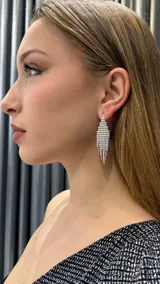 Aros colgantes plateados con forma geométrica y flecos.