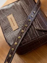 Cartera bandolera marrón con textura tipo piel de cocodrilo, correa larga ajustable y cierre con solapa.