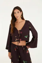 Blusa corta color marrón con estampado de cócteles, escote en V con lazo, mangas largas acampanadas y corte holgado.