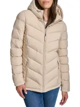 Campera Tommy Hilfiger color beige, acolchada con diseño en forma de V, cierre frontal con cremallera, cuello con capucha, dos bolsillos laterales con cremallera y logo de la marca en la manga izquierda.
