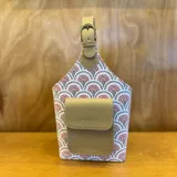 Bolso matero con diseño a cuadros color lila y blanco, con bolsillo frontal color beige y manija superior con hebilla.