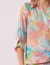 Blusa de gasa estampada con rayas verticales en tonos celeste, azul y blanco. Tiene cuello a la base con escote en V y abertura con botones. Las mangas largas son de largo regulable.