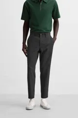 Pantalón slim fit negro confeccionado en tejido con elasticidad en ambas direcciones. Cuenta con bolsillos frontales y traseros de vivo con botón. Cierre frontal con cremallera y botón.