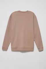 Sudadera de tejido liso color beige, con cuello redondo y puños y ruedo acanalados. Se lleva superpuesta a una camisa de cuadros celestes y blancos.