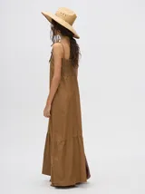 Vestido midi de denim algodón color marrón, con escote recto y tirantes finos ajustables con lazos. El corte es suelto y termina con un ruedo con semi-volado.