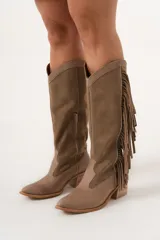 Bota texana de caña alta color visón, 100% cuero hecha a mano en Uruguay, con cierre lateral y taco de 5,5 cm. Tiene flecos en los costados internos.
