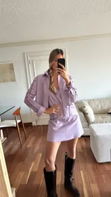 Camisa lila de cuero ovino desgastado, con cuello clásico, cierre frontal con cordones y mangas largas con cutouts y lazos.